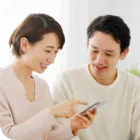 ご利用の流れへのリンクを示す、スマートフォンを一緒に見る夫婦の写真